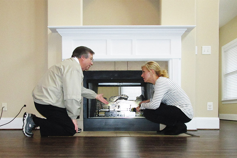 Ben Chambless and Stacy Reed checking a fireplace during a home inspection 